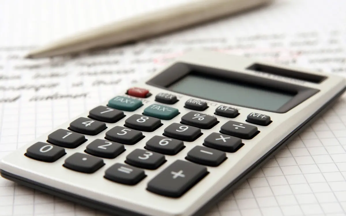 A calculator and pen resting on a sheet of figures