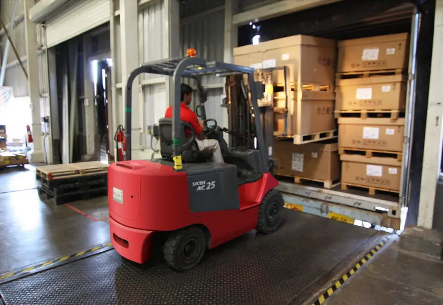 A forklift loading boxed freight at a warehouse dock